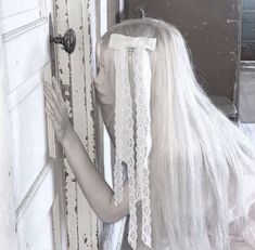 a woman with long white hair is holding onto the door