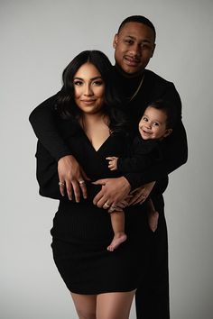 a man and woman holding a baby posing for a photo with their arms around each other