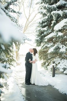 a bride and groom kissing in the snow