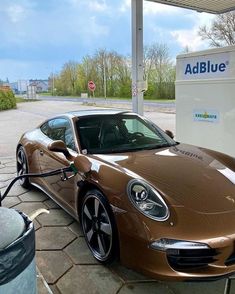 a brown sports car is being charged at an electric charging station with the word adblue on it