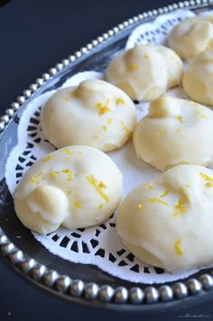 some food that is sitting on a silver platter with white doily around it