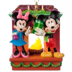 mickey and minnie mouse christmas ornament hanging from a brick wall with lights on