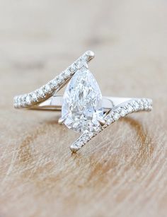 a pear shaped diamond ring on top of a wooden table