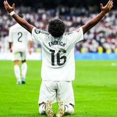 a soccer player sitting on the ground with his hands in the air