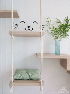 there is a cat head on the wall above some shelves with pillows and plants in vases