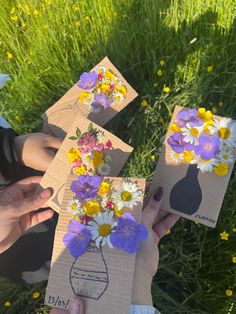 three people holding flowers in their hands on the grass with yellow and purple daisies