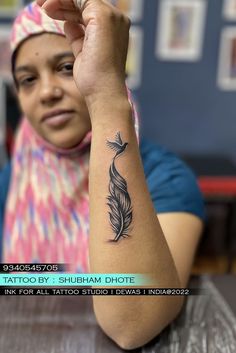 a woman sitting at a table with a tattoo on her arm