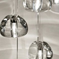 three glass balls hanging from the ceiling in front of a white wall with light reflecting off them