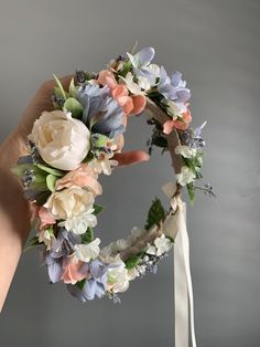 a hand holding a flower wreath with flowers on it