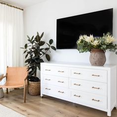 a living room with white furniture and a large tv mounted on the wall