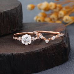 two rose cut diamond rings on top of a piece of wood with flowers in the background