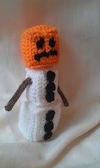 a crocheted snowman with an orange and black hat on it's head