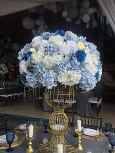 a vase filled with blue and white flowers sitting on top of a table next to candles