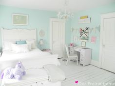 a white bedroom with pastel blue walls and accessories on the bed, nightstands and dresser