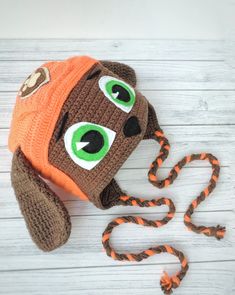 a crocheted hat with eyes and a rope on the ground next to it