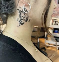 a woman with a butterfly tattoo on her neck and behind her ear, looking at the camera