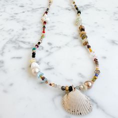 This item is one of a kind. Sustainable shell semi-precious stone necklace. Features vintage Swarovski crystals in sky blue. Made with quartz, hematite, mother of pearl, garnet, shells, freshwater pearls, tiger eye, black onyx, turquoise, brass, peridot, trade beads, rosewood, copper, and Amazonite. Measures 28”. Shell charm measures about 2” long. Handmade in USA. Waterproof. Comes boxed in a linen travel pouch. Non-toxic. Cheap Shell Beaded Strand Necklace, Professional Jewelry, Rose Gold Chain, Trade Beads, Jewelry Cleaner, Travel Pouch, Eye Black, Stone Necklace, Tiger Eye