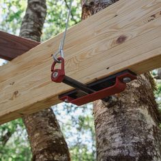 a pair of pliers is attached to a wooden beam in the woods with trees behind