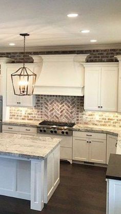 a kitchen with white cabinets and an island in front of a stove top oven under a light fixture