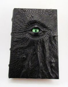 a black leather book with an eye in the center and green eyes on it's cover