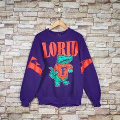 RARE Vintage 90s Florida Gators Football Sweatshirt Florida Crewneck Florida Pullover Florida Sweater Printed Logo Purple Color Men's Fit L Label : Garment Graphics Size : XL (refer the measurement) Made in USA Materials from 50% Cotton 50% Polyester Used Item With Condition 7/10 Refer Picture. No Stain and Holes. Lay Down Flat Measurement : - Width (armpit to armpit) and: 23.5 Inches - Length (shoulder to end of garment): 27 Inches We are selling used clothing with good condition. DO NOT EXPECT Logo Purple, Florida Gators Football, Gators Football, Football Sweatshirt, Florida Gators, Men Fits, Print Logo, Used Clothing, Purple Color