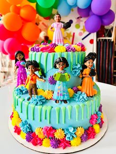 a birthday cake decorated with figurines and decorations on a table in front of balloons