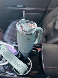 a cup with a straw in it is sitting on a car console next to other items