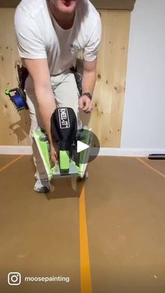 a man in white shirt holding a skateboard on top of a hard wood floor