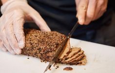 a person in white gloves cutting into a piece of cake with a knife on top of it