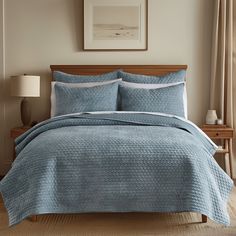 a bed with blue bedspread and pillows in a bedroom