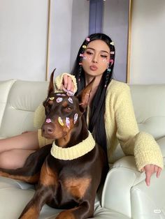 a woman sitting on top of a white couch next to a brown and black dog