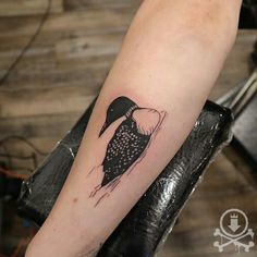 a black and white bird tattoo on the right arm, with dots in it's body