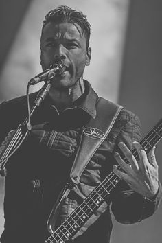 a man holding a guitar and singing into a microphone