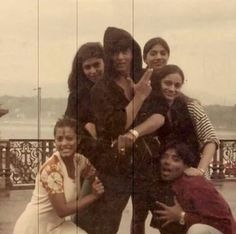 a group of people standing next to each other in front of a fence and water