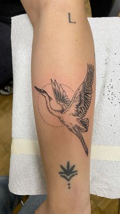 a tattoo on the leg of a woman with a bird in it's left arm