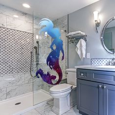 a bathroom with a shower, toilet and sink in it's center area is decorated with an image of a mermaid on the wall