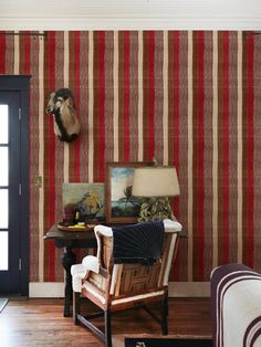 a living room with striped wallpaper and wooden flooring, including an animal head mounted on the wall