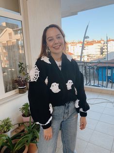 a woman standing in front of a window wearing a black sweater with white teddy bears on it