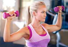 a woman lifting two dumbbells in a gym