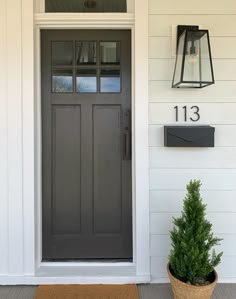 the front door of a house with a potted plant and mailbox on it