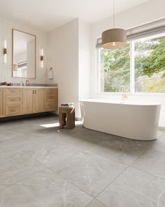 a large white bath tub sitting in a bathroom next to a sink and a window