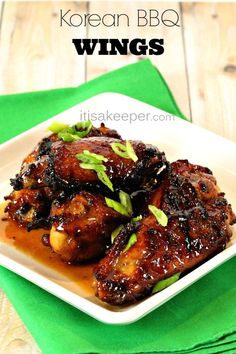 korean bbq wings on a white plate with green napkin and wooden table in the background