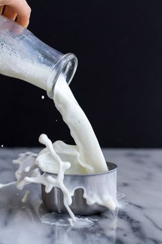 someone is pouring milk into a metal container