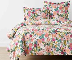 a bed covered in pink and green floral print comforter with matching pillowcases