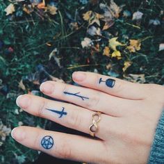 a woman's hand with two tattoos on it and an arrow ring in the middle