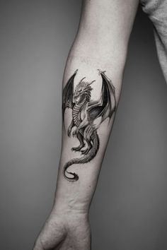 a man's arm with a black and white dragon tattoo on the left forearm