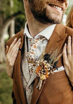 a man in a suit and tie with flowers on his lapel