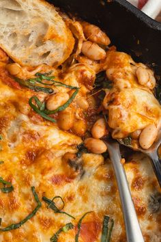 a casserole dish with white beans and spinach on it, in a cast iron skillet