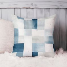 a blue and white pillow sitting on top of a fur covered bed next to a wooden headboard