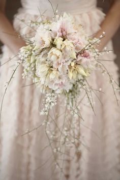 a bridal holding a bouquet of white and pink flowers in it's hands